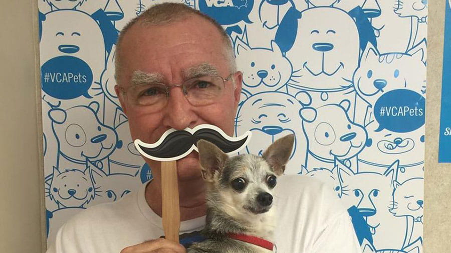 Man holding a small dog and a mustache at VCA Miracle Mile Animal Hospital